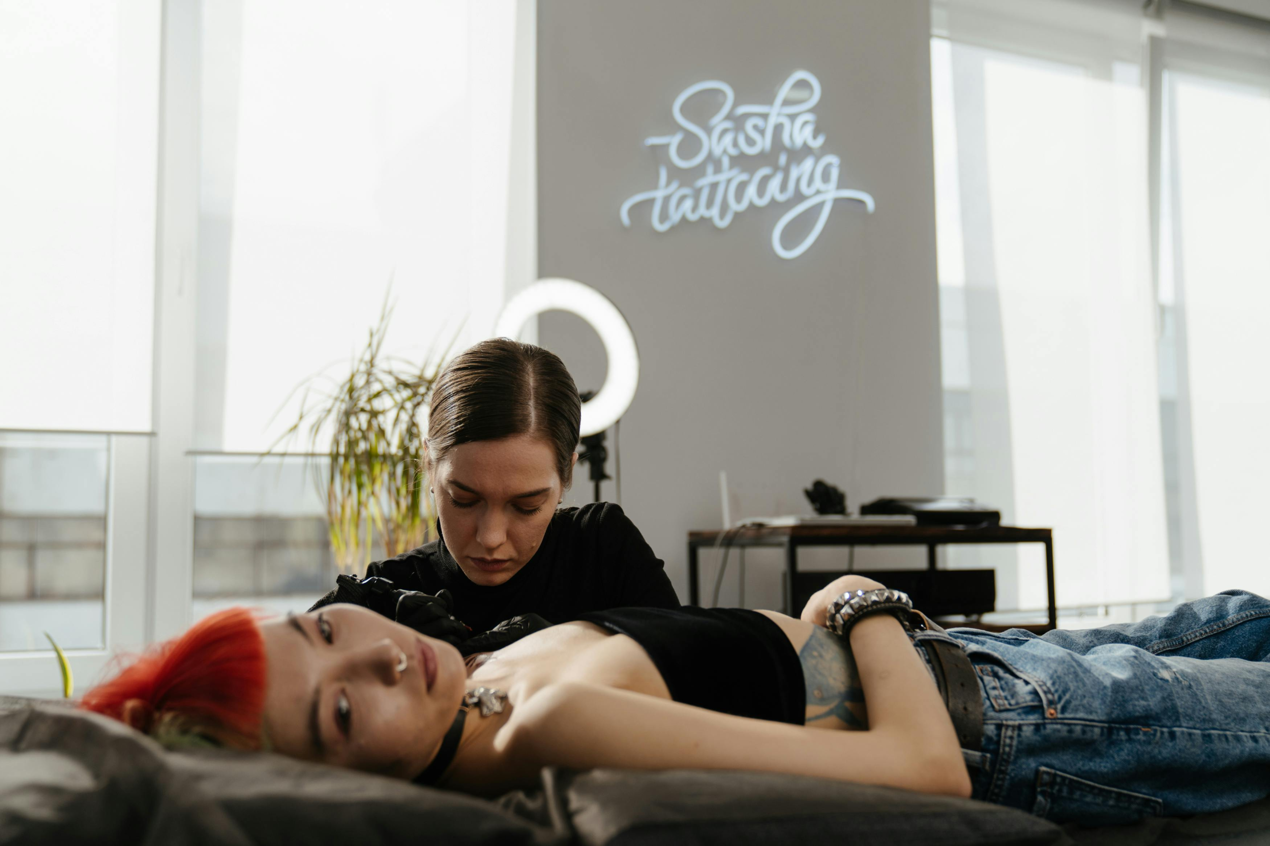 Tattoo artist managing social media content on a laptop in their studio